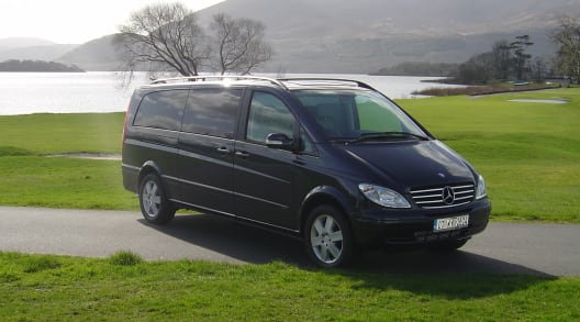 A black four seater Mercedes V Class luxury mini van on the grass on a sunny day