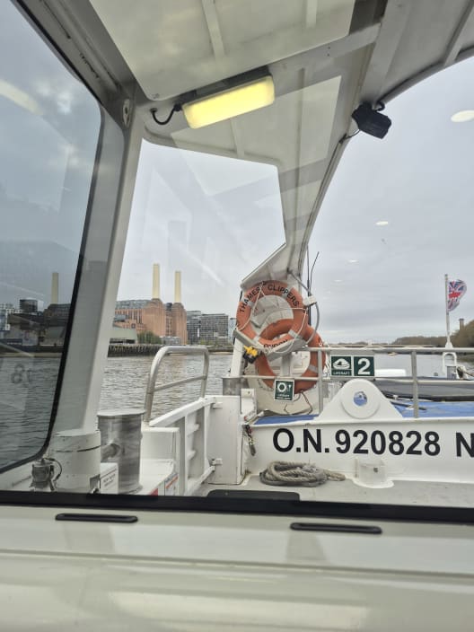 Looking out the window of a river boat on the Thames, with a life ring attached to the white exterior railings.