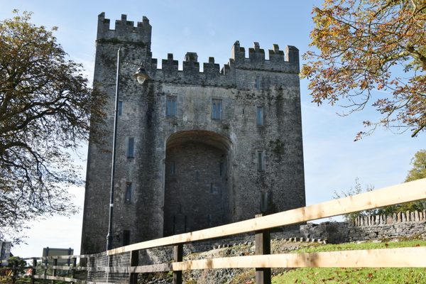 The keep of Bunratty Castle seen across the timber walkway, under a clear blue sky