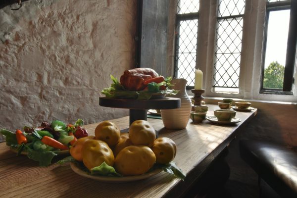 A table laid with fruit and bottles beside a leaded window inside Bunratty Castle