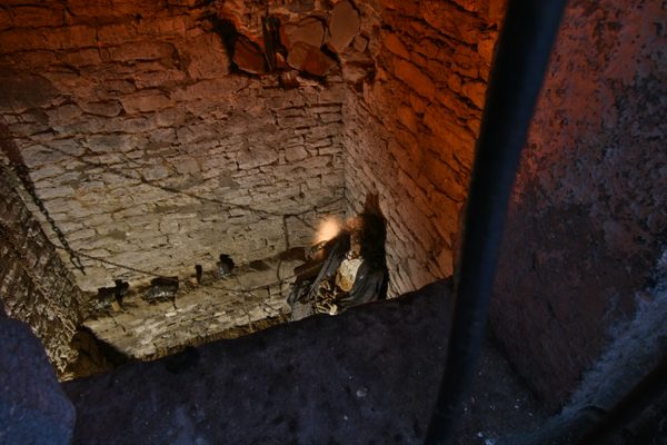 Looking down over the stone stairs into the dungeon at Bunratty Castle, with straw on the floor and a figure below