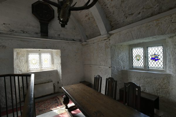 A smaller vaulted chamber inside Bunratty Castle, with a long polished table, high-backed chairs and mullioned windows of stained glass