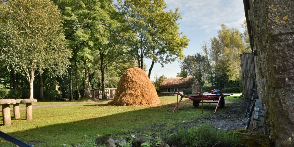 A tall haystack in the farmyard at Bunratty Folk Park, with the old stone barn alongside