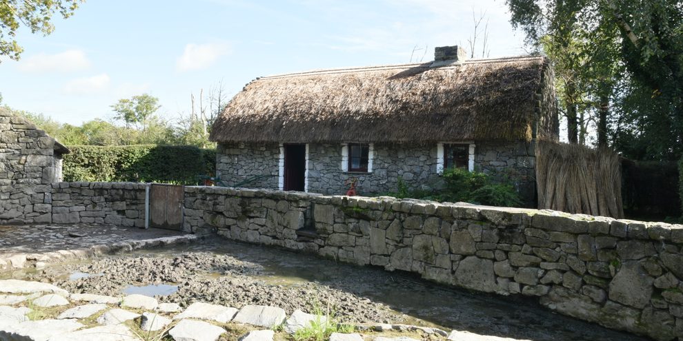 A thatched cottage set behind a low stone wall at Bunratty Folk Park