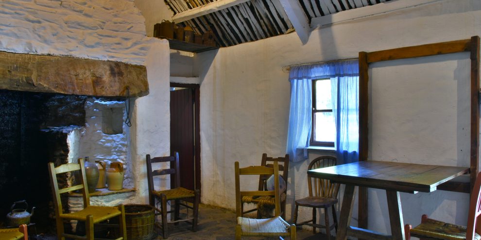 The kitchen of one of the farmhouses at Bunratty Folk Park, with a table, chairs and whitewashed walls