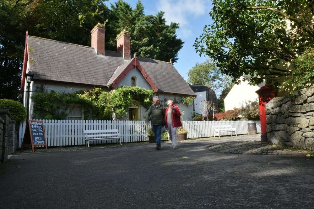 A village street at Bunratty Folk Park, with visitors passing a whitewashed cottage