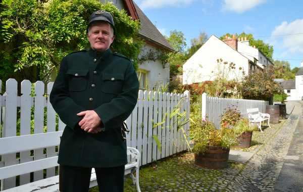 A man in a period constable's uniform standing outside a cottage at Bunratty Folk Park