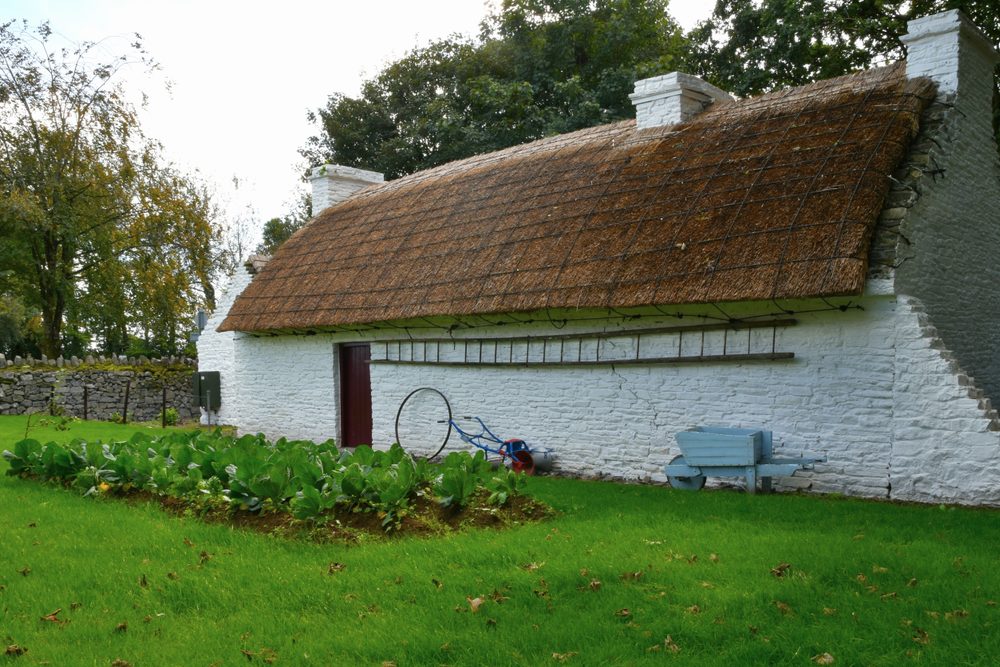 A thatched cottage with a turf stack stacked against its gable