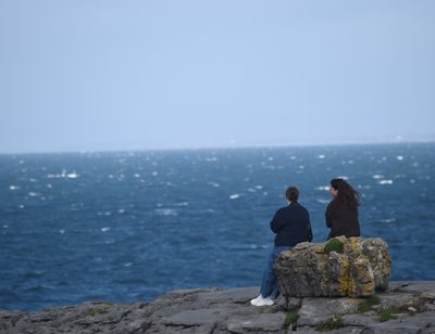 Two guests sitting together on the limestone coast of the Burren, County Clare
