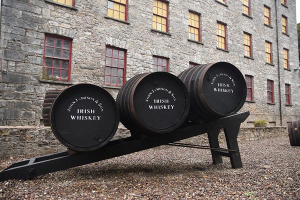 Three wooden whiskey barrels on display outside the historic distillery buildings