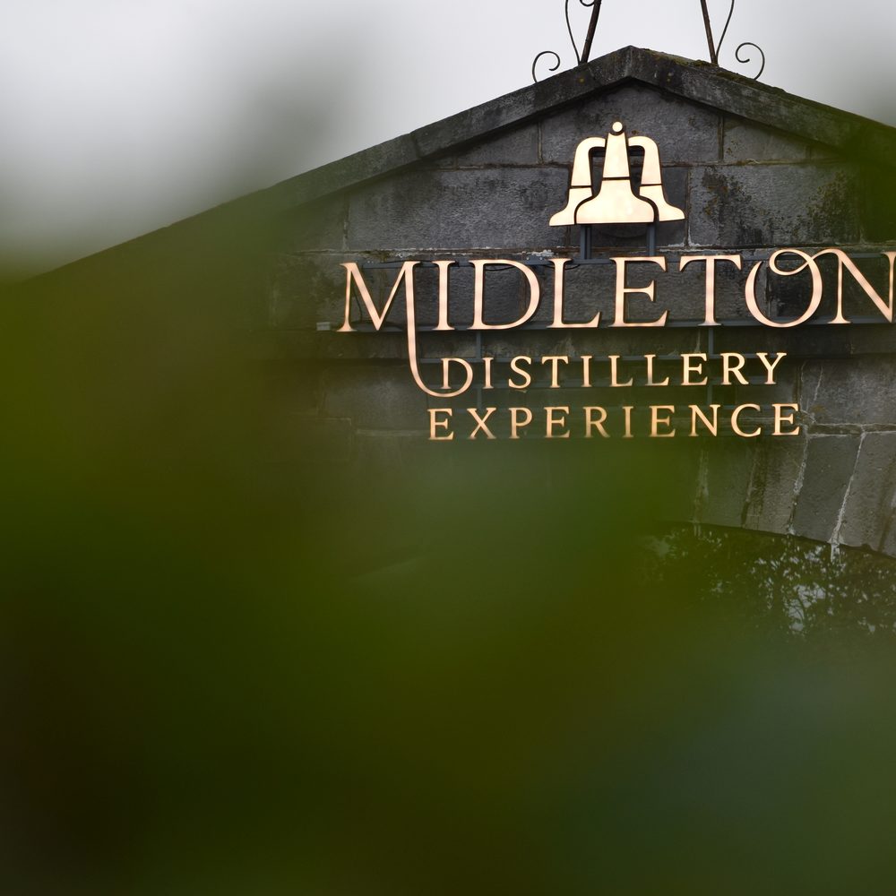 The gold 'Midleton Distillery Experience' sign on the stone entrance to Midleton Distillery Experience
