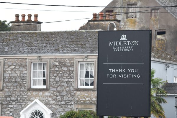 The 'Midleton Distillery Experience - Thank you for visiting' sign in front of the stone building