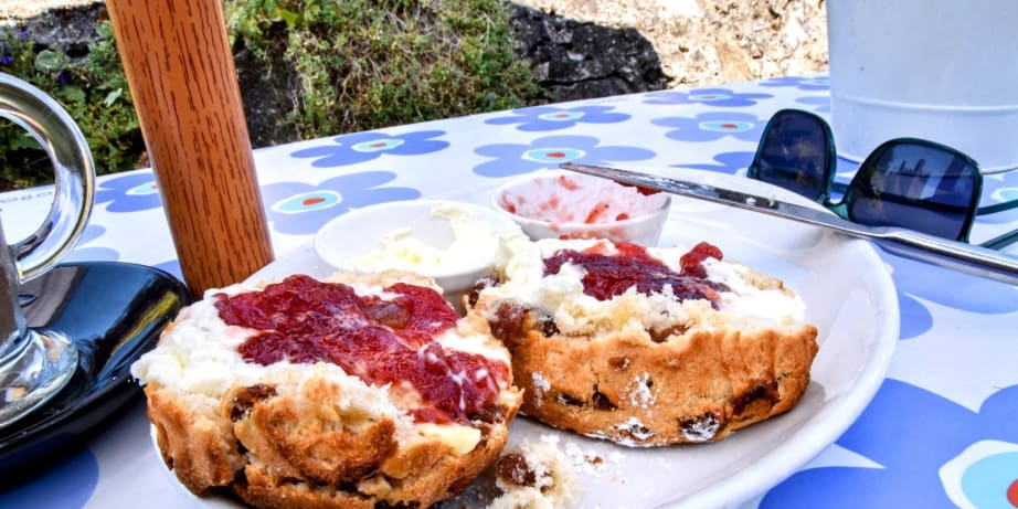 A traditional scone with jam and cream alongside an iced latte